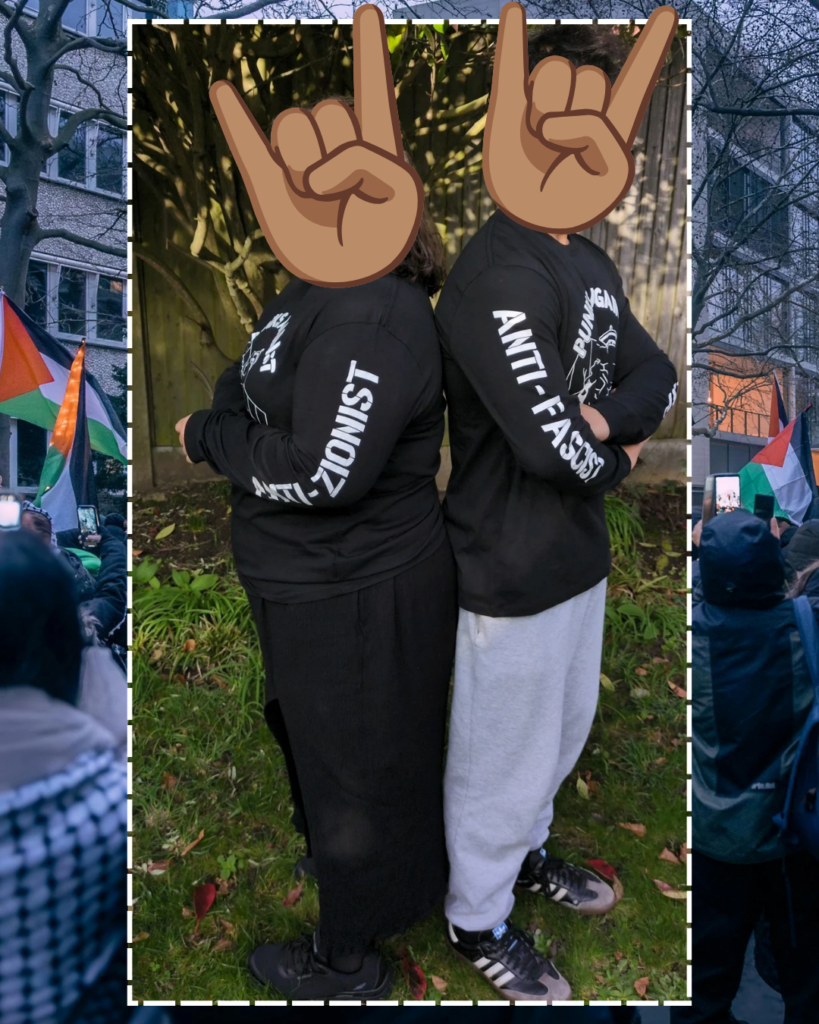 A background showing a Palestine protest. In the middle with a white outline, a photo of two individuals with a long-sleeve Punks Against Apartheid t-shirt on, standing with their backs to each other in a garden and looking forwards. Their heads have been replaced by large 'metal hands' emojis. The centre of the shirt shows the PAA logo (a fist with a spikey bracelet punching through the apartheid wall), and each exposed arm shows the phrases: 'ANTi-ZIONIST' and 'ANTI-FASCIST'.